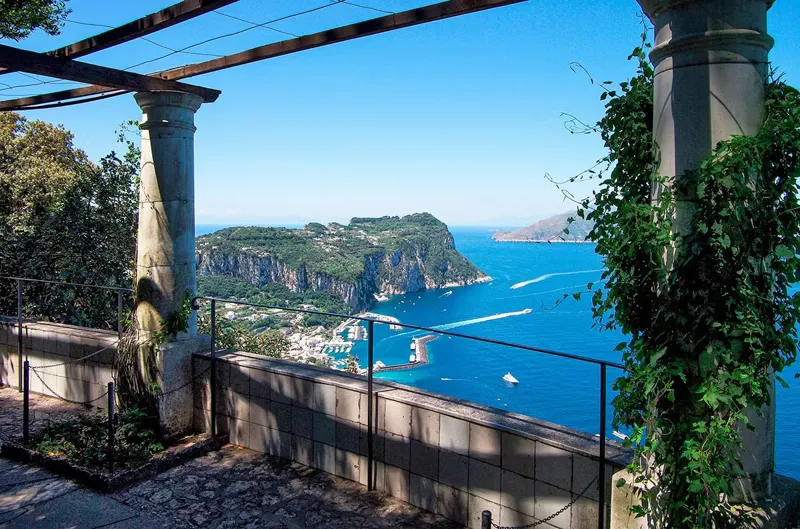Axel Munthe på Capri och drömmen om San Michele Det finns platser som känns nästan magiska – där historia, skönhet och mänsklig envishet smälter samman. En sådan plats är utan tvekan Villa San Michele på Capri. Här, på denna solbadade klippa i Anacapri, förverkligade den svenske läkaren och författaren Axel Munthe sin livsdröm. Det blev inte bara ett hem, utan ett monument över hans livssyn, hans kärlek till djur och hans längtan efter ljus. Vem var Axel Munthe Axel Martin Fredrik Munthe föddes 1857 i Oskarshamn och växte upp i en familj där både bildning och medmänsklighet värderades högt. Hans far var apotekare och lärde honom tidigt vikten av att hjälpa andra – något som skulle prägla honom hela livet. Som ung lockades Munthe av medicin och började studera i Uppsala innan han fortsatte sina studier i Frankrike. Vid 22 års ålder blev han den yngste medicine doktorn i Frankrikes historia, ett rekord som väckte uppmärksamhet i hela Europa. Men hans väg blev långt ifrån enkel. Efter några år som framgångsrik läkare i Paris drabbades han av utmattning och hälsoproblem. Han lämnade stadens brus och reste söderut – till Italien. Där, på den vackra ön Capri, skulle han finna sin tillflykt och sitt kall. När drömmen om Capri blev verklighet När Axel Munthe först steg i land på Capri 1888 möttes han av ett ljus och en stillhet han aldrig tidigare upplevt. Han bosatte sig tillfälligt i Villa Damecuta men fann snart sin sanna plats högre upp på berget, i byn Anacapri. Där, bland olivträd, ruiner och vidsträckta vyer, köpte han ett gammalt kapell tillägnat ärkeängeln Mikael – San Michele. Han bestämde sig för att bygga om det förfallna kapellet till ett hem. Enligt hans egen berättelse var det ruinerna av ett tempel tillägnat Isis, men de flesta forskare menar att han snarare lät fantasin spela fritt. Oavsett vilket, skapade Munthe något som få människor ens vågat drömma om. Bygget av Villa San Michele Byggandet av villan började 1895 och pågick i flera år. Munthe arbetade sida vid sida med lokala hantverkare, och med hjälp av den italienske konstnären Aristide Sartorio fick projektet sin slutliga form. Villan byggdes i en klassisk stil med ljusa väggar, höga valv och öppna ytor som släppte in solljuset. Han ville, som han själv uttryckte det, att huset skulle vara "öppet för solen, vinden och havets röst". Den böljande pergolan som leder mellan huset och kapellet är i dag en av Capris mest fotograferade platser. Munthe fyllde sitt hem med antika skulpturer, pelare, urnor och konstföremål – en del fynd från trakten, men många köpta i Rom och Neapel. Han gav varje föremål en berättelse, ibland sann, ibland påhittad. Hans hem blev en spegelbild av hans egen personlighet: intellektuell, nyfiken och något excentrisk. 🌿 Visste du detta? Axel Munthe kallade Villa San Michele sitt ”tempel för ljus”. Huset ligger 325 meter över havet och bjuder på utsikt över Neapelbukten och Vesuvius. I trädgården står en 3200 år gammal egyptisk sfinx som blickar ut mot havet – en symbol för evighet och visdom. Ett hem för både människor och djur Munthe var inte bara läkare för människor – han var även en hängiven djurvän. På Capri kämpade han mot fångst av flyttfåglar och köpte till slut hela berget Barbarossa ovanför villan för att skydda fåglarna. Där anlades ett fristadsområde för ornitologer som än i dag används för fågelstudier. Han lät hundar, apor, katter och fåglar leva fritt i villan. För Munthe var kärleken till djur en naturlig del av mänskligheten. Hans filosofi var enkel: den som inte respekterar djur förstår inte livet. Axel Munthe som författare och mytmakare År 1929 publicerade Munthe sin bok Boken om San Michele, en självbiografisk berättelse fylld av anekdoter, filosofi och sagolik symbolik. Den blev en internationell bästsäljare och översattes till över 40 språk. Genom boken skapade han sin egen myt – den vise läkaren som byggde sitt paradis på Capri. I boken blandas sanning och fantasi, humor och sorg, medicin och mystik. Han skriver om sjukdom, död och kärlek, men alltid med glimten i ögat. Den röda manteln som anden bär i boken symboliserar livet självt – vackert, farligt och flyktigt. Kändisar och kungligheter på San Michele Under de år Munthe bodde på Capri blev hans hem en mötesplats för tidens kulturella och kungliga elit. Författaren Henry James, konstnären P.S. Krøyer och till och med Oscar Wilde besökte honom. Men den mest betydelsefulla gästen var utan tvekan den svenska kronprinsessan Victoria av Baden. Hon och Munthe utvecklade en nära relation som varade livet ut. Victoria blev hans patient, vän och förtrogna. Deras samarbete inspirerade henne att bygga Solliden på Öland – ett svenskt sommarresidens som i mycket påminner om San Michele, med sina ljusa väggar, skulpturer och medelhavskänsla. ☀️ Citat från Axel Munthe ”Jag vill att mitt hus ska vara öppet för solen, vinden och havets röst – som ett grekiskt tempel, och ljus, ljus, ljus överallt!” Detta uttryck fångar essensen av Axel Munthes livsfilosofi och den anda som genomsyrar Capri och Villa San Michele än i dag. Ett liv mellan ljus och skugga Trots sin framgång och sitt paradis på jorden var Axel Munthe en plågad själ. Han led av migrän, sömnlöshet och tilltagande synproblem. Det starka ljuset på Capri förvärrade hans ögonsjukdom, och han tvingades till slut flytta till sitt torn Torre di Materita längre västerut på ön. Ändå lämnade han aldrig San Michele helt. Villan förblev hans andliga hem, även när kroppen inte längre orkade. Han fortsatte skriva, donera pengar till fattiga och ta hand om djur. Under första världskriget arbetade han dessutom frivilligt för brittiska Röda korset – trots att han då var närmare sextio år gammal. Ett arv som lever vidare När Axel Munthe avled 1949 i Stockholm, hade han redan bestämt att San Michele skulle doneras till svenska staten. Hans önskan var att platsen skulle bli ett hem för svenska forskare, konstnärer och studenter som ville studera i Italien – människor som delade hans kärlek till kultur och humanism. I dag förvaltas villan av en stiftelse knuten till Svenska institutet i Rom. Huset är öppet för allmänheten och besöks varje år av tusentals människor som vill se hans verk, hans trädgård och den ikoniska sfinxen som blickar ut över havet. Trädgården som vann Italiens hjärta Trädgården runt Villa San Michele är en fristad för både växter och själar. Här blommar kamelior, jasmin, apelsinträd och vinrankor, och doften av Medelhavet ligger tung över pergolan. Den har till och med utsetts till Italiens vackraste privata park – en hyllning till Munthes känsla för balans mellan natur och arkitektur. Ett hus som fortfarande talar När du vandrar genom Villa San Michele idag är det lätt att förstå varför Axel Munthe blev kvar här så länge. Ljuset som faller över marmorstatyerna, tystnaden mellan cypresserna och den eviga utsikten över havet berättar hans historia bättre än någon bok. Du känner nästan hans närvaro, som om han fortfarande går där mellan pelarna, med sin hatt på sned och en hund i hälarna. Kanske, i det milda skenet från Neapelbukten, hittar du samma ro som han en gång fann – den ro som för alltid förknippas med Axel Munthe på Capri.